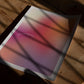 Unframed “This is my happy place” gradient art print lying on a wooden floor with window shadows.