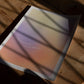 Unframed pastel gradient art print reading “Focus on the journey, not the destination” lying on a wooden table beneath window shadows.