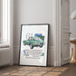 Black-framed 1961 Jaguar E-Type collage artwork leaning against a paneled wall beside a window and open doorway.