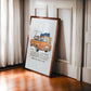 Dark wood-framed orange BMW 2002 artwork leaning beside sheer curtains in a sunlit paneled room.