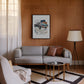 Black-framed 1969 Chevrolet Camaro collage artwork displayed above a gray sofa in a wood-paneled living room.