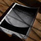 Unframed Artemis II lunar surface art print lying on a wooden table in patterned sunlight.