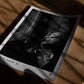 Unframed Artemis II astronaut art print lying on a wooden table in dramatic sunlight and shadow.
