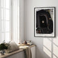 Black-framed Artemis II Goodnight Moon art print hanging in a sunlit room above a window bench with cushions, books, and flowers.