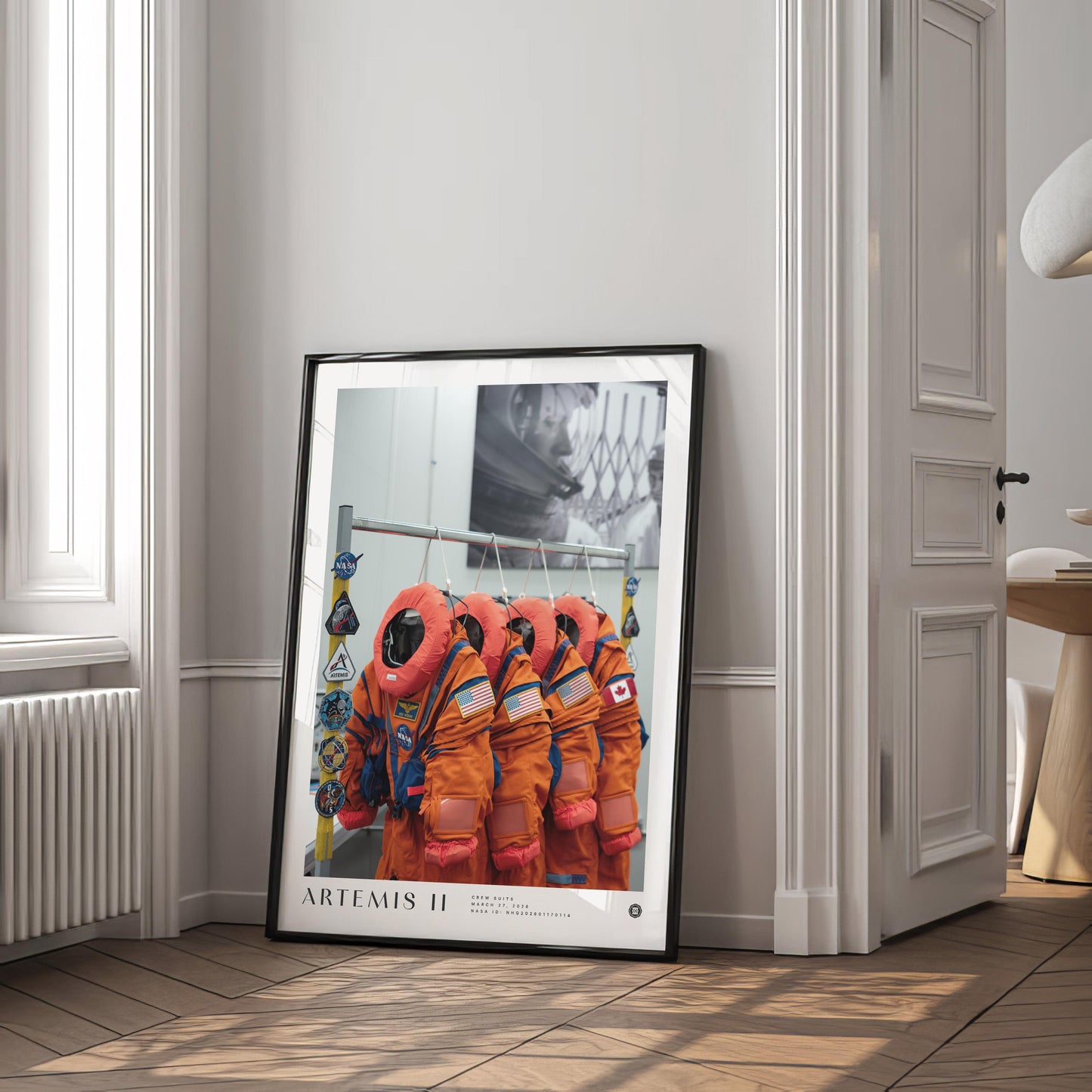 Black-framed Artemis II crew-suit art print leaning against a wall in a bright interior.