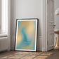 Black-framed abstract teal and yellow art print reading “Get back to center,” leaning near a doorway.