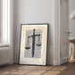 Black-framed Sword & Scales artwork displayed in an interior setting beside a tall window and open paneled door.