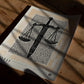 Unframed Sword & Scales art print lying on a wooden surface in patterned sunlight and shadow.