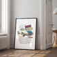 Black-framed 1965 Porsche 911 collage artwork leaning against a paneled wall beside a window and open doorway.