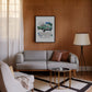 Black-framed 1961 Jaguar E-Type collage artwork displayed above a gray sofa in a wood-paneled living room.