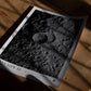 Unframed Artemis II Shadows Across Vavilov Crater art print lying on a wooden floor in dramatic window shadows.