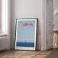 Black-framed Artemis II Orion capsule recovery art print leaning beside a window in a bright interior.