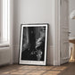Black-framed Artemis II astronaut art print leaning against the wall in a bright room beside a window and open doorway.