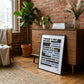 Black-framed free speech legal cases typography art print leaning against a wooden dresser in a brick-walled room.