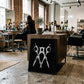 Black-framed black and white scissors artwork displayed against a wooden cabinet in a hair salon.