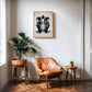 Oak-framed monochrome DJ turntable artwork hanging above a tan leather chair and potted plants.