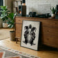 Black-framed monochrome DJ turntable artwork leaning against a wooden record cabinet beneath audio equipment.