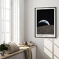Black-framed Artemis II Earthset art print hanging above a sunlit window seat with books and greenery.