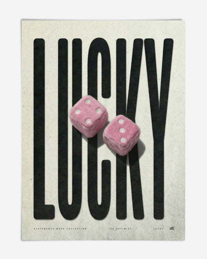 Unframed LUCKY art print featuring oversized black lettering and two pink fuzzy dice.